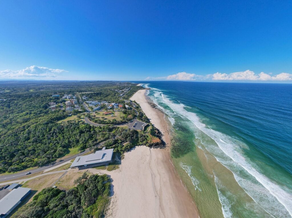 aerial view of a long coastal beach and headland
