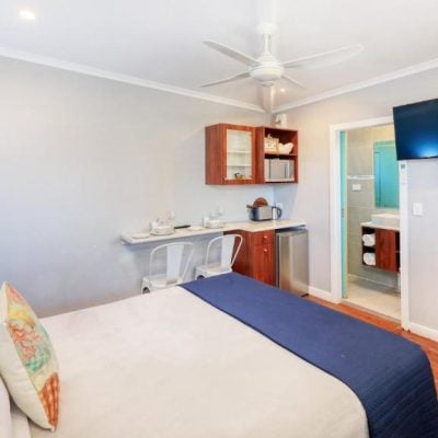 A view inside a bright motel studio room with light grey walls and dark wood floors.