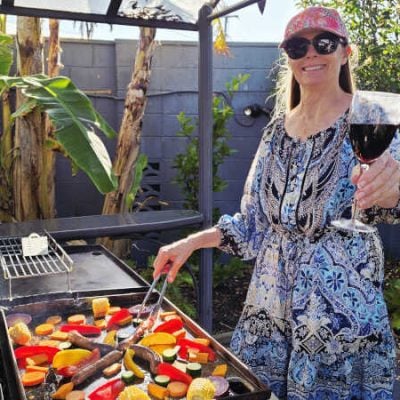 smiling-woman-with-a-pink-cap-and-sunglasses-is-cooking-colourful-vegetables